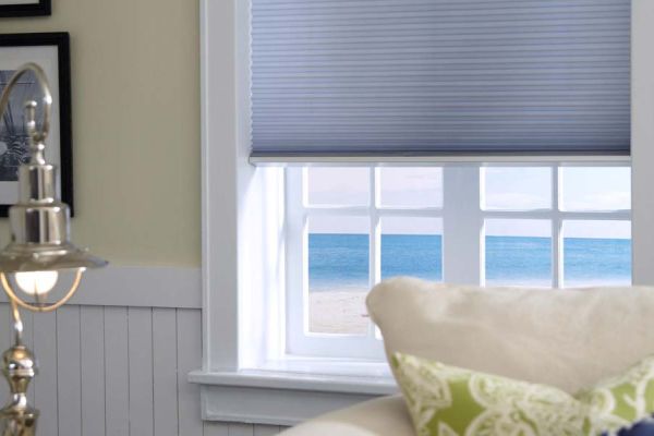 blue honeycomb shades on a window overlooking the ocean